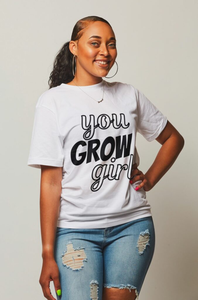 African-American woman in a white t-shirt with black text that reads "You GROW Girl!"